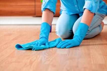 Close up of a woman's hands as she kneels on the floor wiping it with a rag.